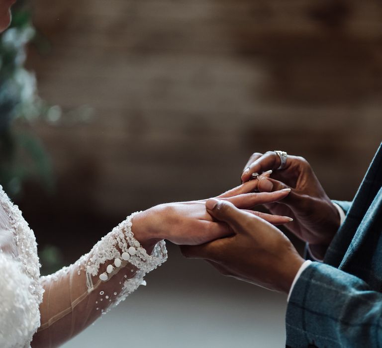 The groom slips a wedding ring onto the bride's finger