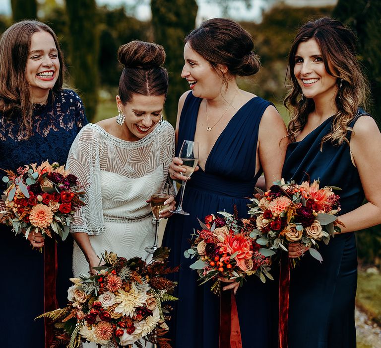 Bride stands with her bridesmaids in deep blue dresses 