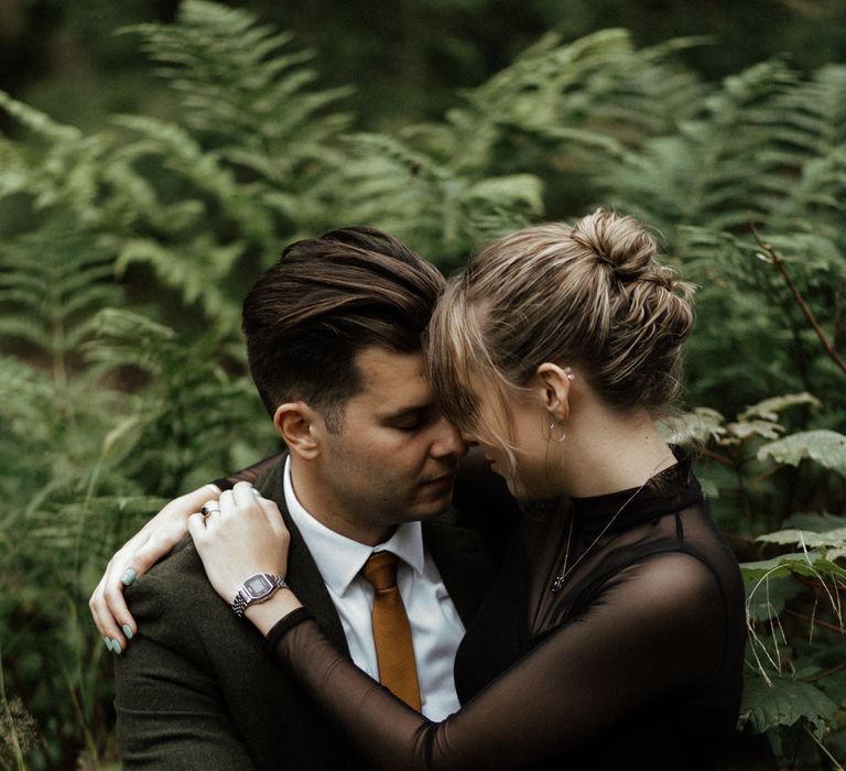 Bride sits on grooms lap during wedding day wearing black dress