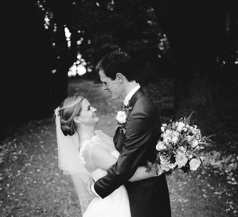 Black & white image of bride & groom embracing on wedding day