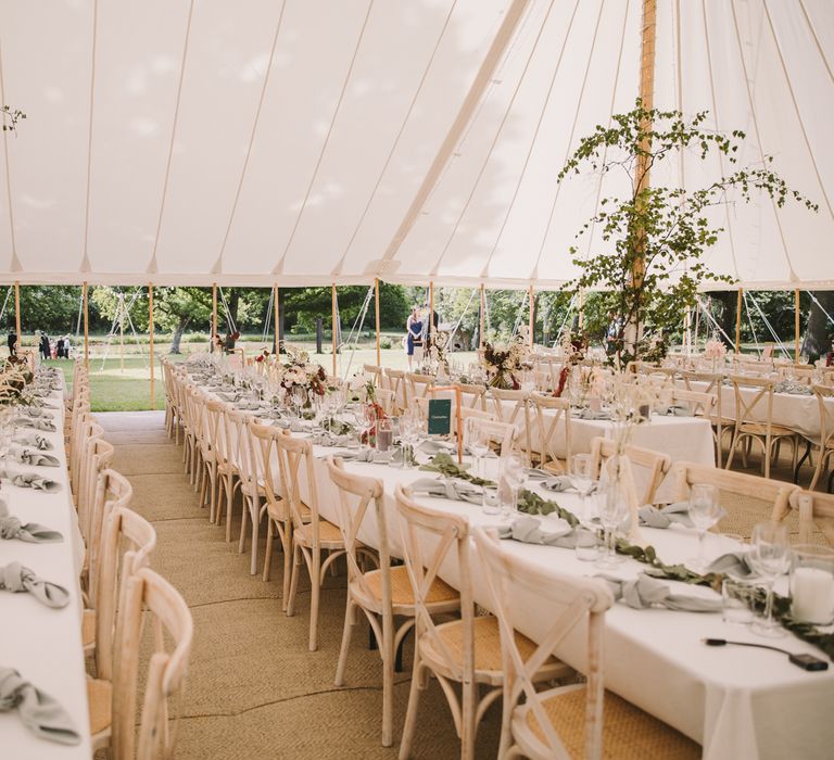 Banquet tables line marquee with white linen table clothes and floral decor