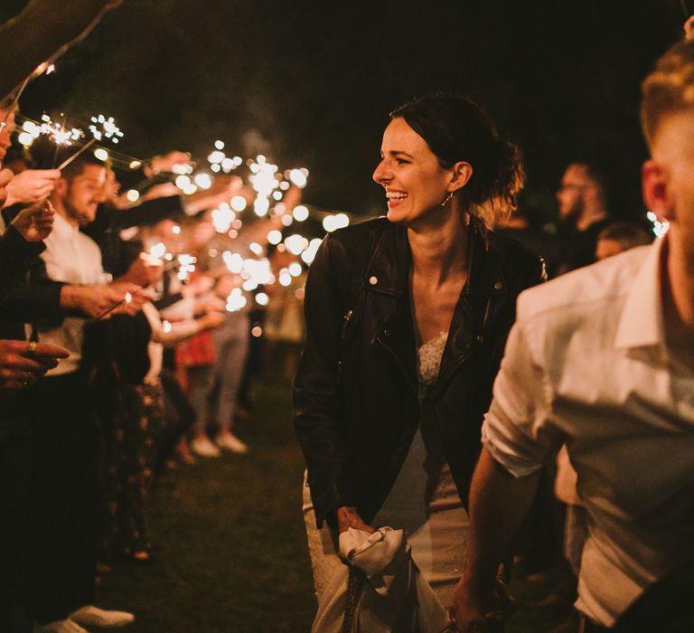 Bride & groom run through archway of wedding party whilst they hold sparklers above them