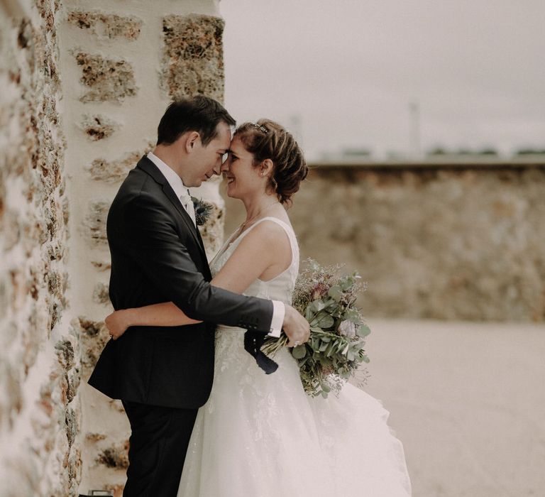 The bride and groom embracing with the groom holding her bouquet