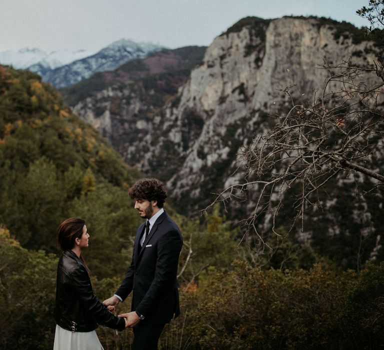 The bride and groom holding hands in front of an amazing forest landscape