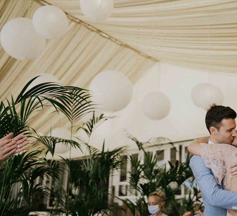 Bride and groom kiss under lanterns at Lusty Glaze wedding ceremony