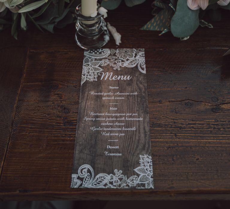 Menu stationery with wooden background surrounded by florals