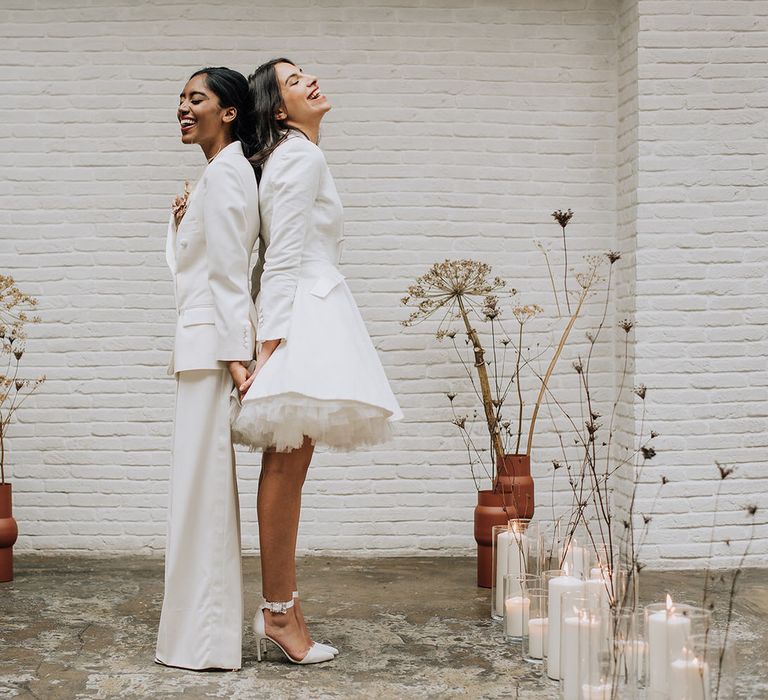 Brides standing back to back at the top of the aisle for their all white wedding