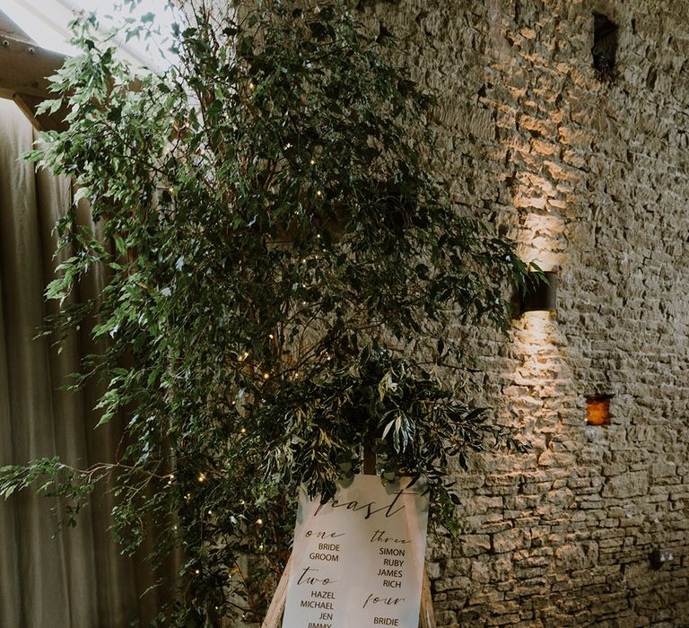 Table plan on a wooden easel with natural wedding flowers decor 