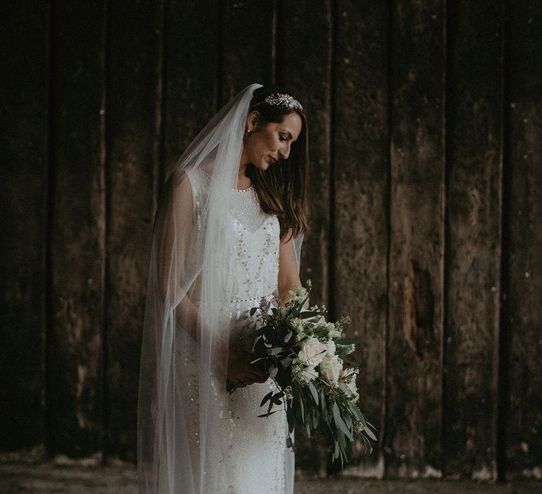 Bride looks down on her wedding day as she holds floral bouquet