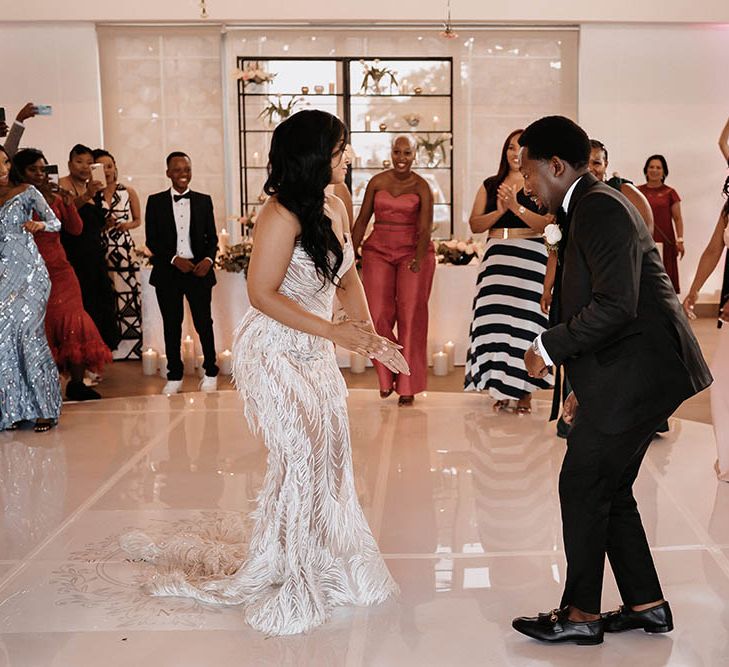 Bride and groom dancing on the white shiny dance floor at their black-tie wedding 