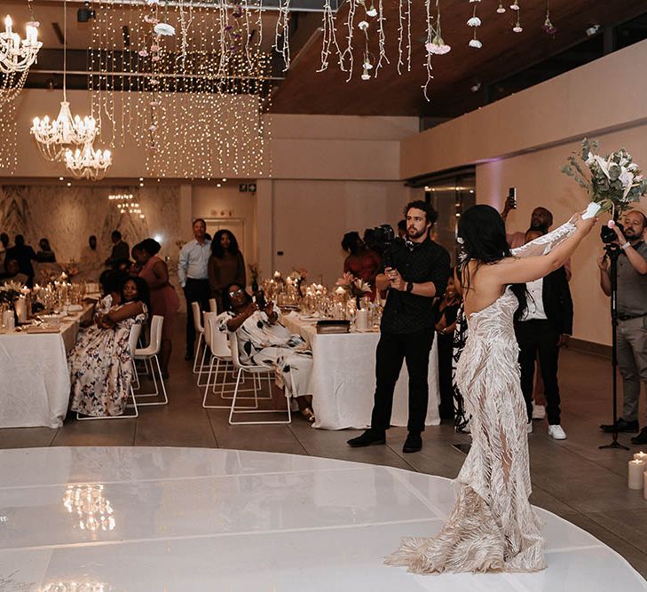 Bride in a strapless feather wedding dress about to throw the bouquet 