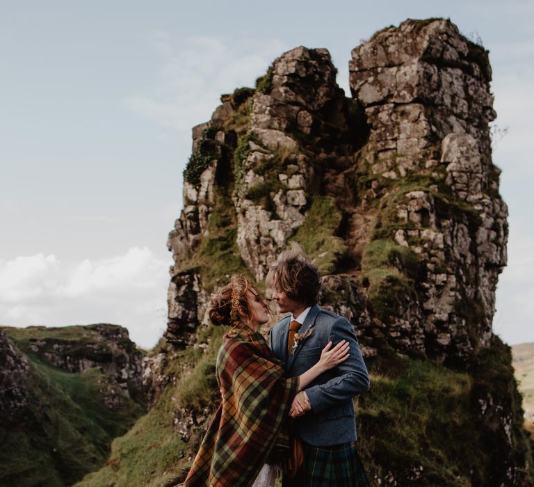 Bride & groom stand in front of rocks 