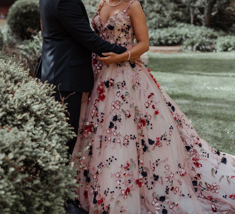 Bride & groom look lovingly at one another on their wedding day as bride wears floral appliqué wedding gown