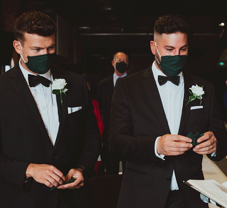 Groomsmen in black tuxedo's with white rose buttonhole flowers and DIY forest green face masks 