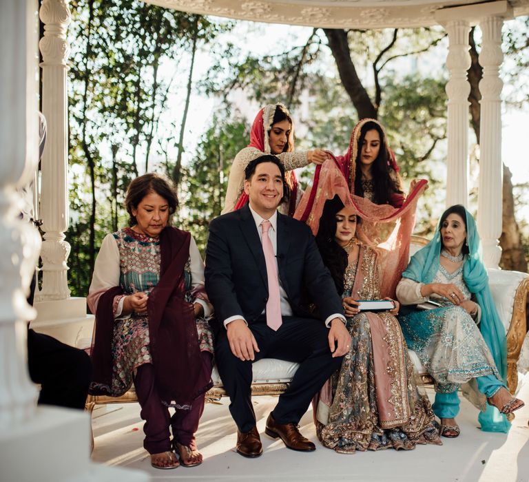 Brides veil is lifted during traditional wedding ceremony outdoors