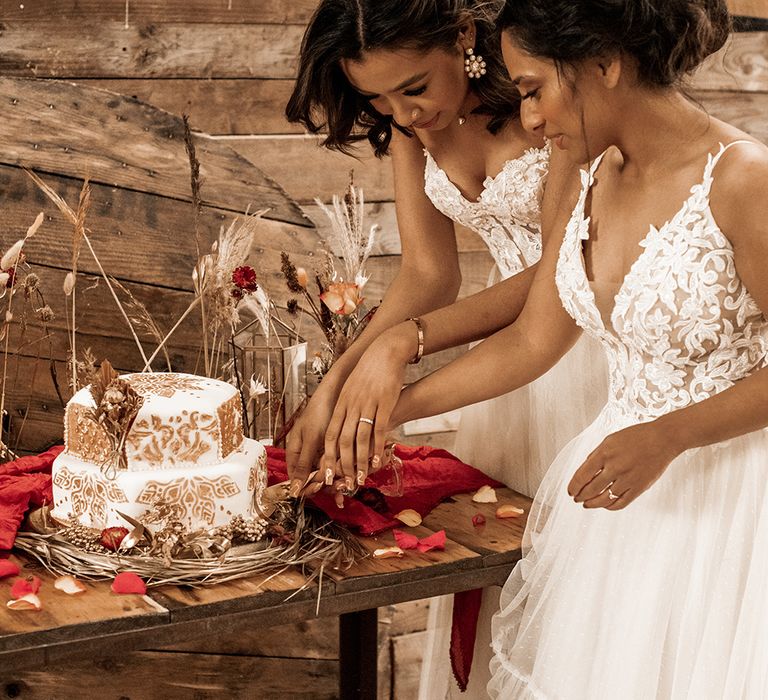 Two brides cutting their two tier Moroccan wedding cake at The Barn at Drovers 