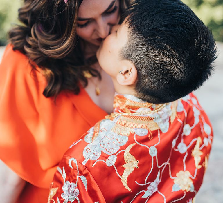 Brides kiss on their wedding day as bride wears pink floral crown