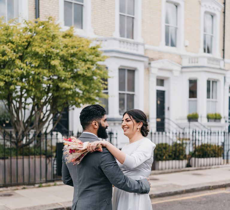 Bride & groom embrace outdoors within the streets of Chelsea on their wedding day