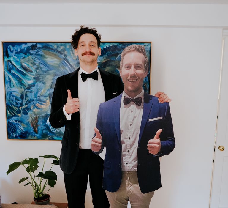 Groom stands with cardboard cut out of friend on his wedding day