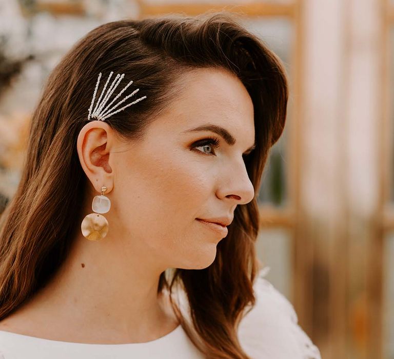 Bride with side swept hair wearing layered grips and stylish earring bridal accessories 