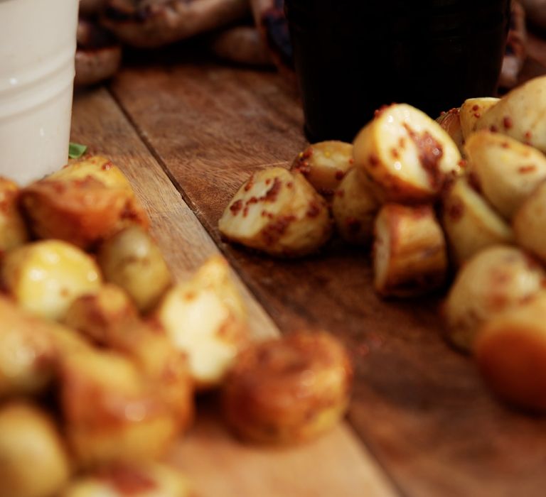 Roasted potato on wooden board complete with salad in bowl