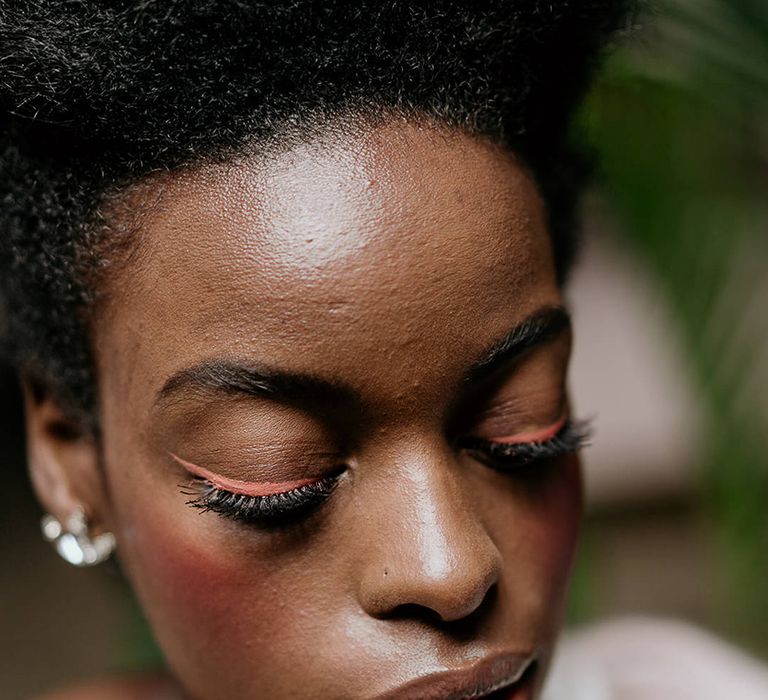 Black bride wearing a light pink winged eyeliner with blush cheeks and clear gloss