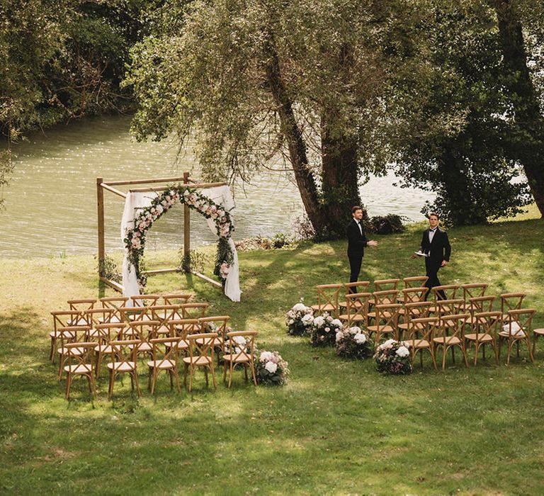 Intimate outdoor wedding ceremony at Chateau Lagorce with wooden chairs and white and pink floral arch 