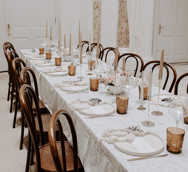 neutral wedding table decor with coloured goblets, taper candles and a patterned tablecloth 