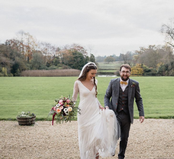 White brunette bride and white groom with beard smile as they walk toward venue