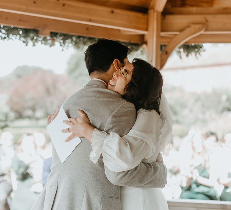 Bride hugs her groom with a big smile on her face