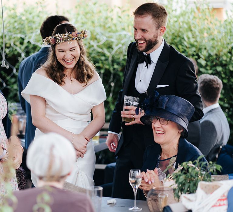 Bride & groom laugh with wedding guests on their wedding day