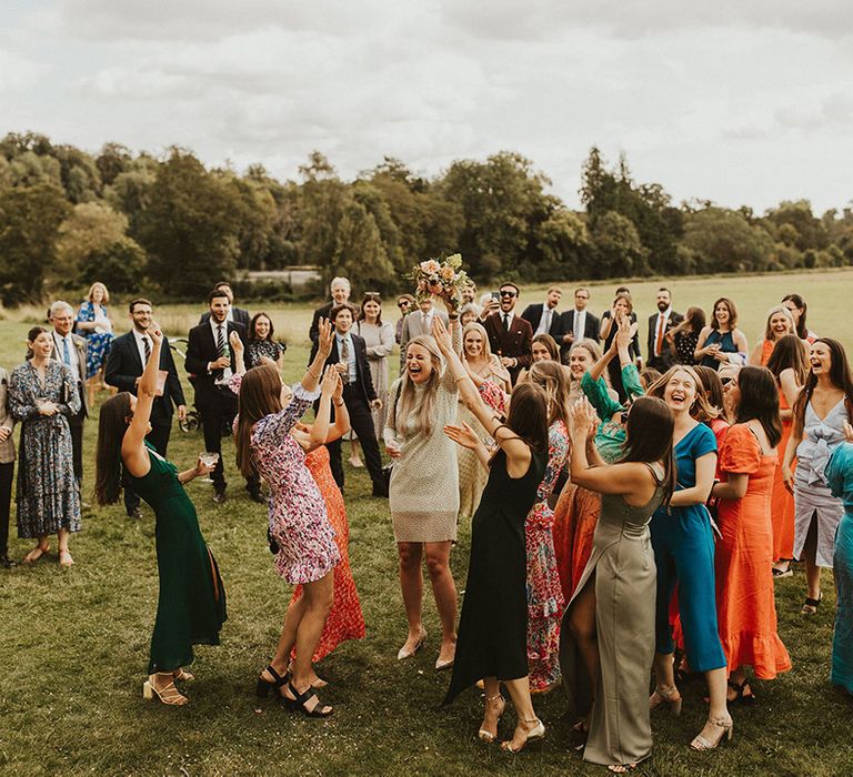 Wedding guests catch bridal bouquet outdoors