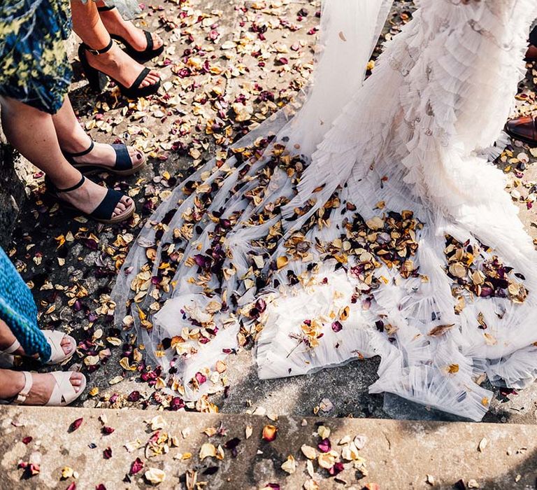 Colourful confetti on the floor covers the train of brides wedding gown