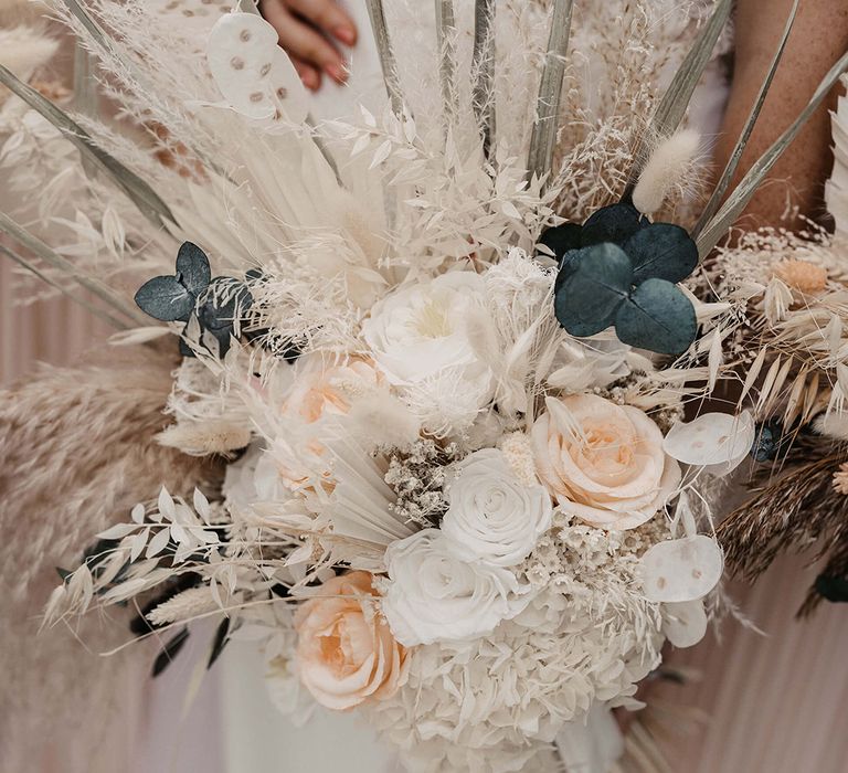 Bride holds floral bouquet filled with pastel coloured flowers