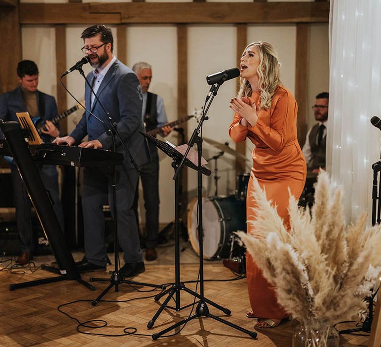 Bridesmaid in burnt orange bridesmaid dresses sings during ceremony