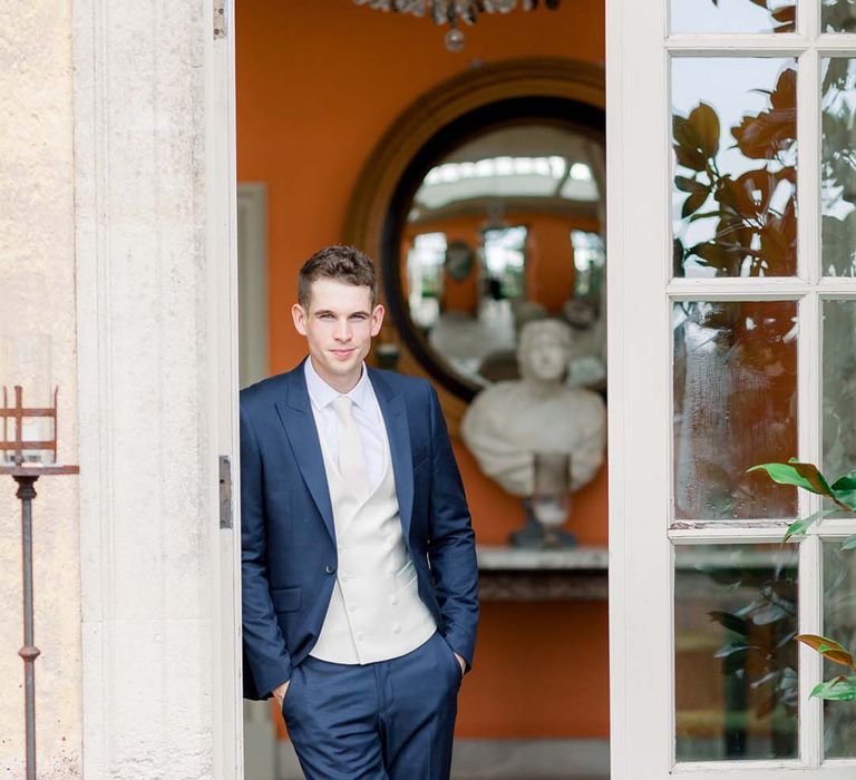 Groom leans on door at The Orangery 