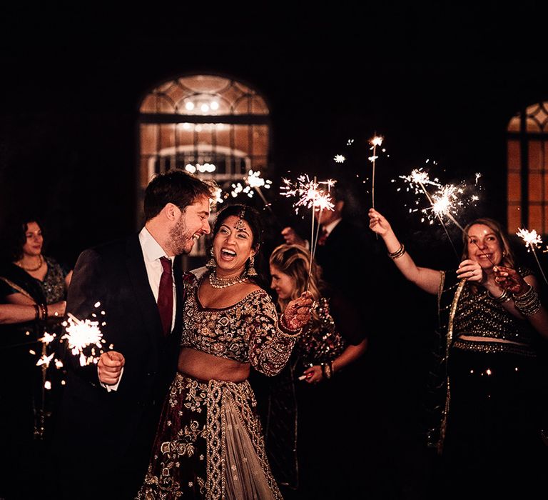 Groom & Bride hold sparklers at the evening of their wedding at Minley Manor