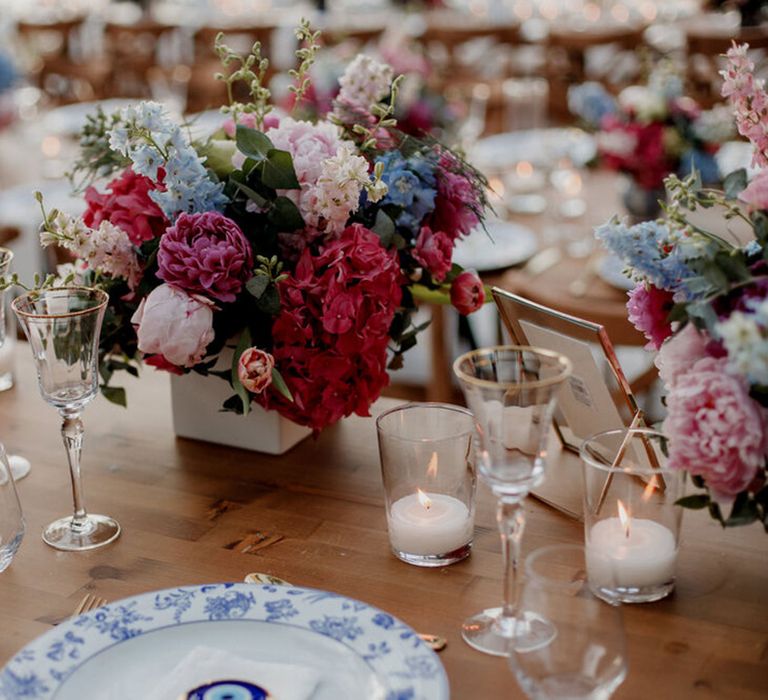 Bright florals line the middle of table for Greek wedding 