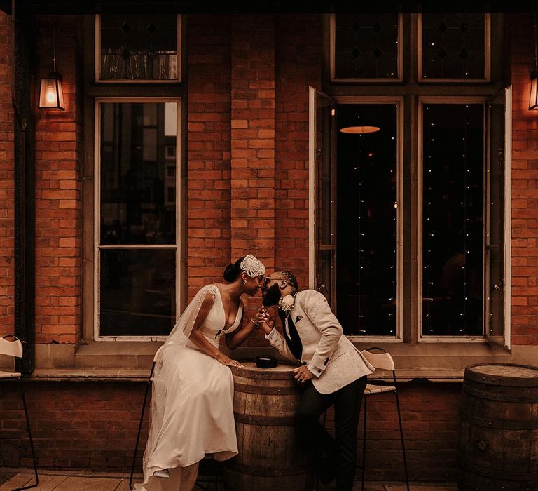 Bride and groom kissing outside a pub in Birmingham in a Pronovias wedding dress with Watteau train and a white tuxedo jacket 