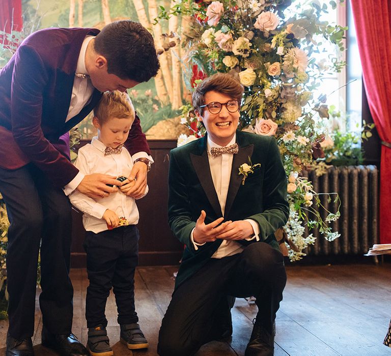 Grooms with young wedding guest in matching floral bow ties at quirky wedding venue