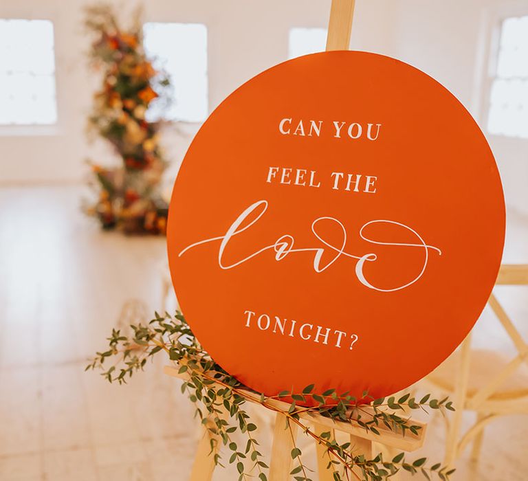 Orange circle wedding sign on a wooden easel at golden wedding 