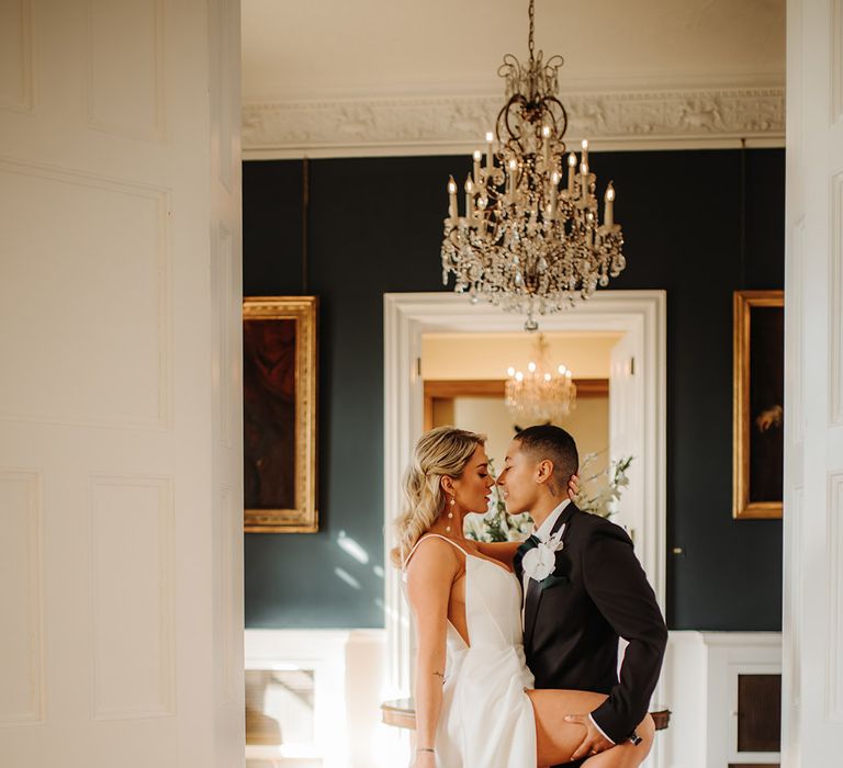 Bride in a princess wedidng dress with side slit holding her leg up for her partner to hold in a tuxedo 