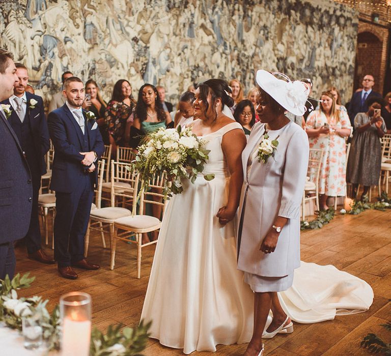 Mother of the bride walks the bride down the aisle to meet the groom at the altar for wedding ceremony