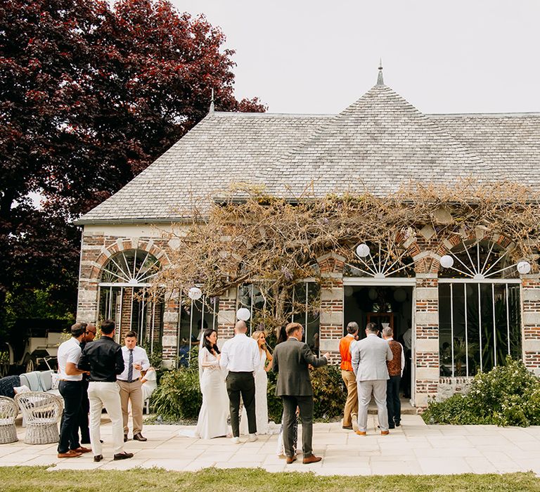 Wedding guests socialise outside of the venue 