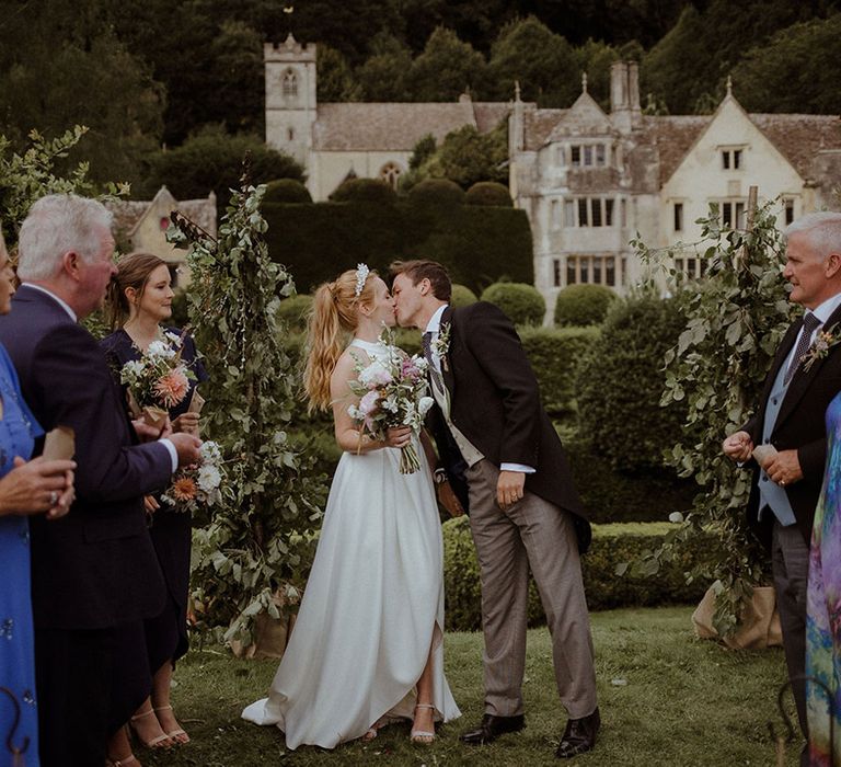 Bride and groom share a kiss after their handfasting wedding ceremony 