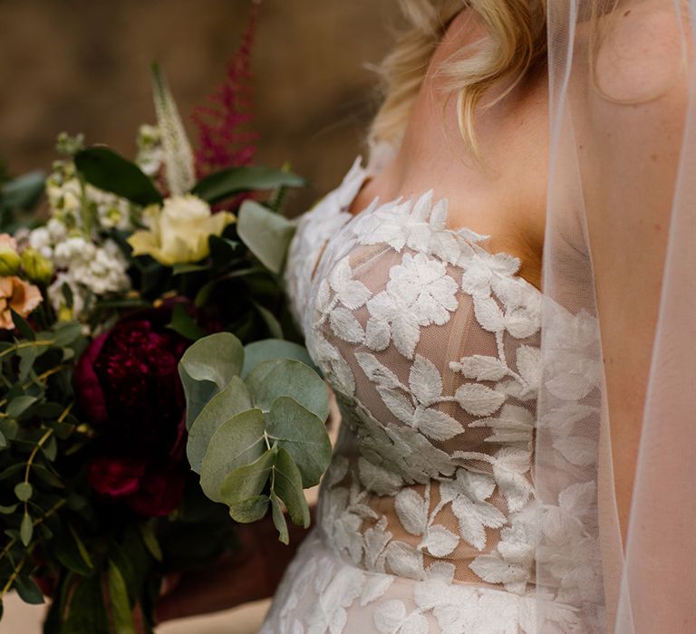 Bride in strapless lace Lillian West wedding dress with red and white flower wedding bouquet 