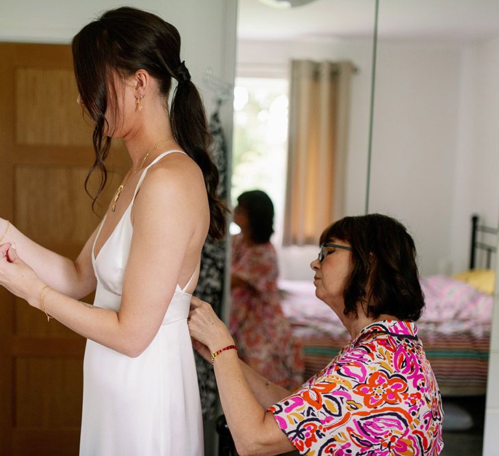 Brides mother helps her with her DIY wedding gown on the morning of her wedding day