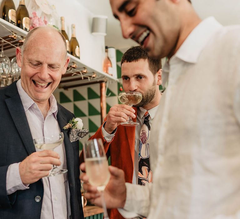 Wedding guests & groom sip Prosecco during wedding reception 