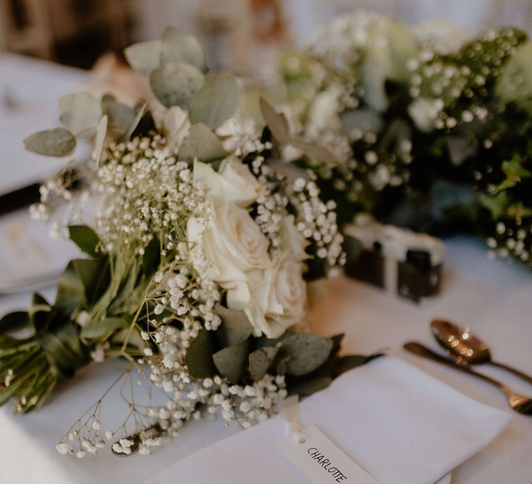 Classic and simple wedding stationery and table setting with plain white name place cards and gold cutlery 