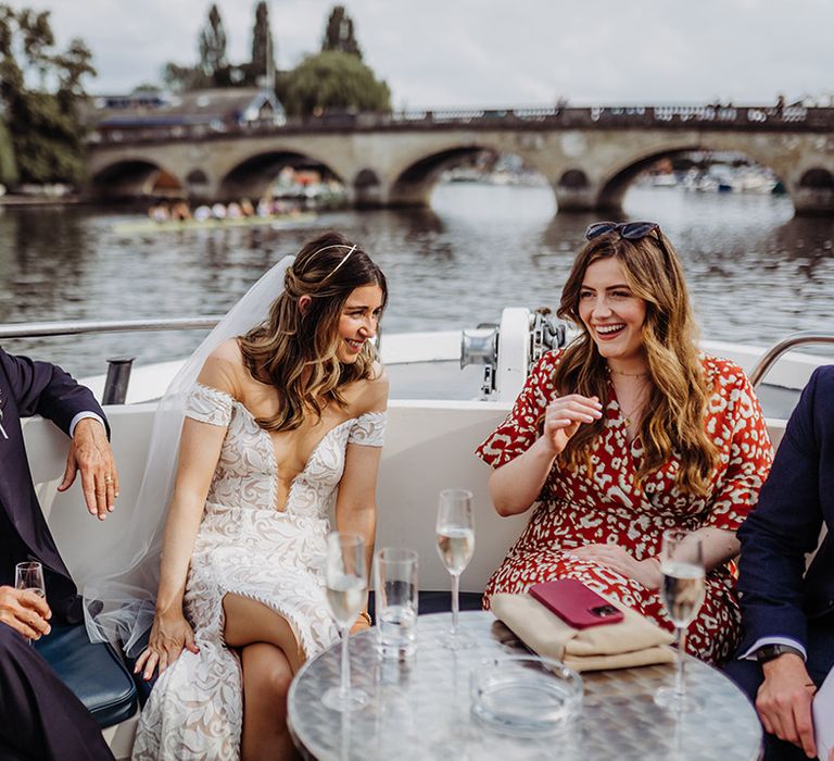 Bride laughs and socialises with wedding guests on a boat 